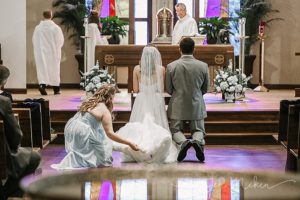 maid of honor fluffs the brides dress at the alter