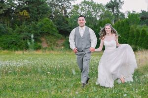 bride and groom running thru a field at veltres wedding and event center plum pa