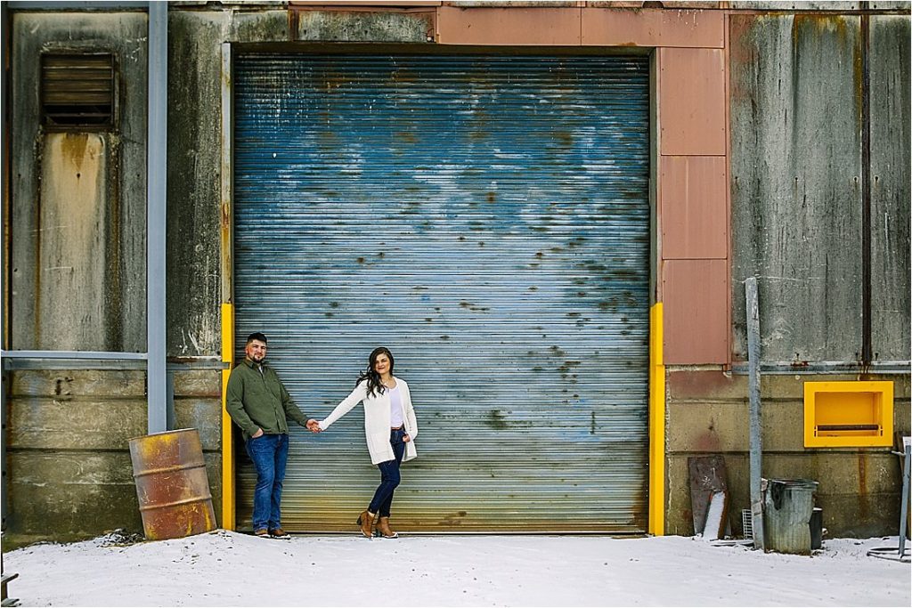 engaged couple in front of peeling steel painted garage door