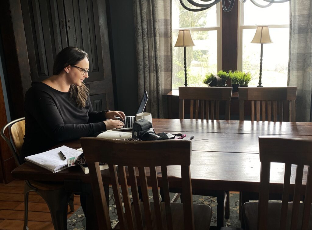 women working from a laptop at the dining room table