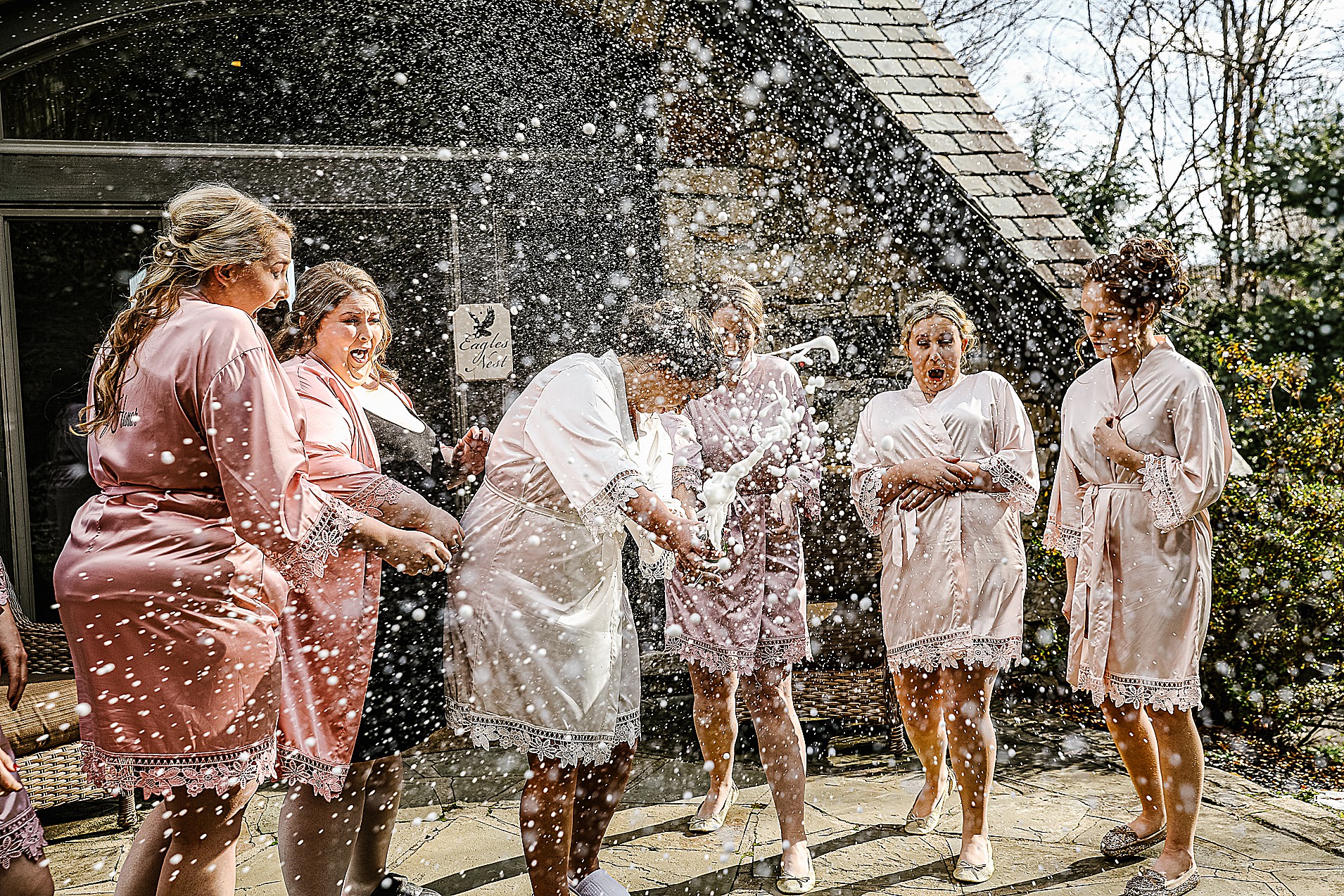 Bride popping and spraying champagne with her bridesmaids